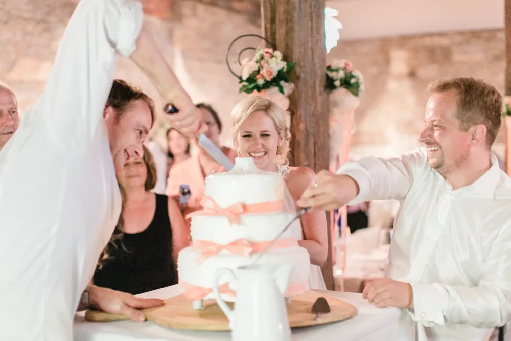 Anschnitt der Hochzeitstorte in Hochzeitslocation Winzerhof Stahl mit Hochzeitsfotograf bei Würzburg