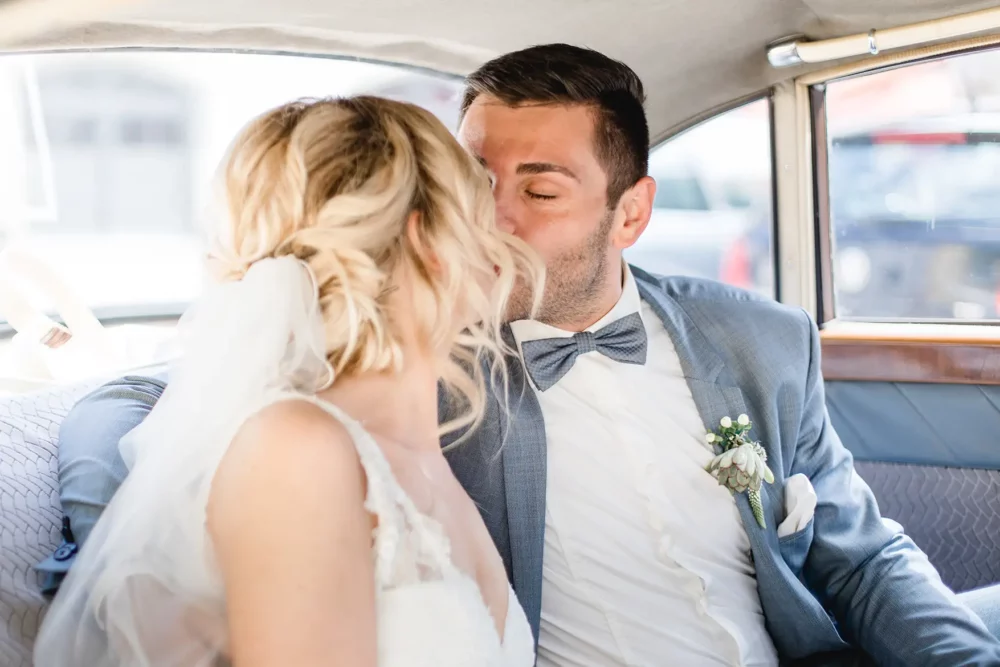 hochzeitsfotografin-freihof-prichsenstadt-055 Brautpaar küsst sich im Brautauto vor Hotel Freihof in Prichsenstadt