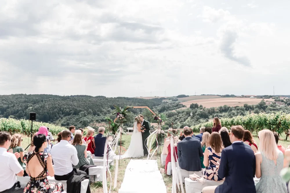 Brautpaar küsst sich bei freier Trauung im Weinberg bei Würzburg