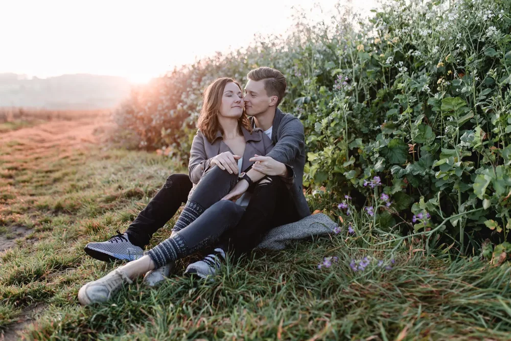 paarshooting-amberg-sonnenuntergang-15 Kuschelndes Paar vor Wildblumenfeld bei Paarshooting in Amberg