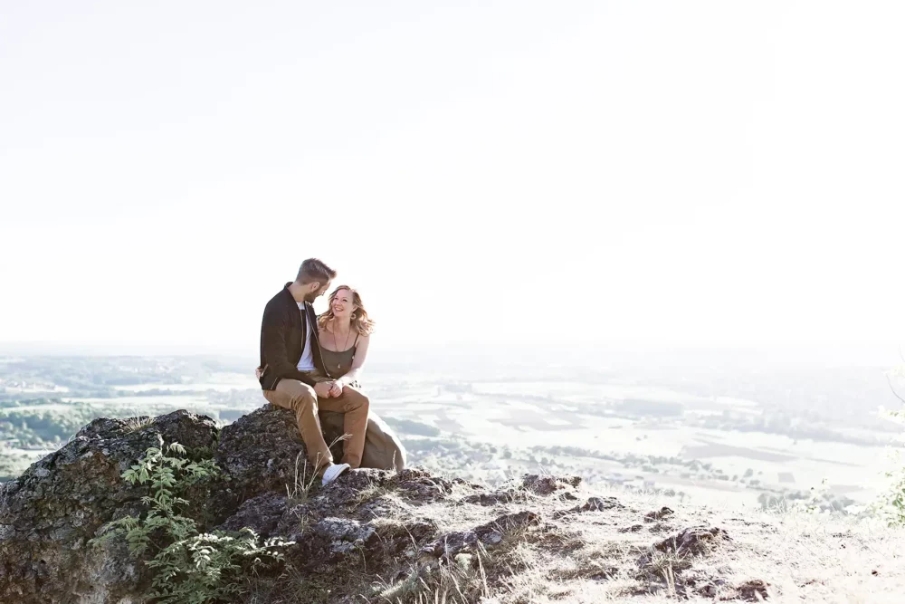 paarshooting-nuernberg-09 Paar sitzt auf Bergkuppe mit Blick über Franken bei Pärchenshooting nahe Nürnberg