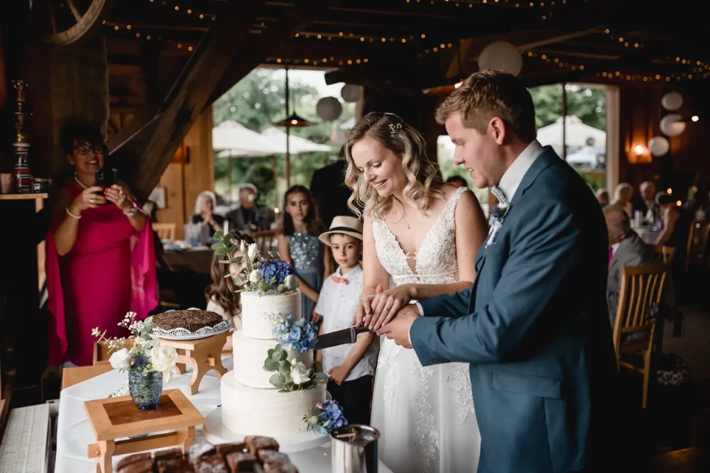 Anschnitt der Hochzeitstorte von Bäckerei Menzel zur Scheunenhochzeit mit Fotografin in der Pflugsmühle, Hochzeitslocation bei Nürnberg